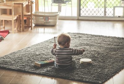Baby van enkele maanden oud die speelt met een eenvoudige rammelaar op een zachte ondergrond